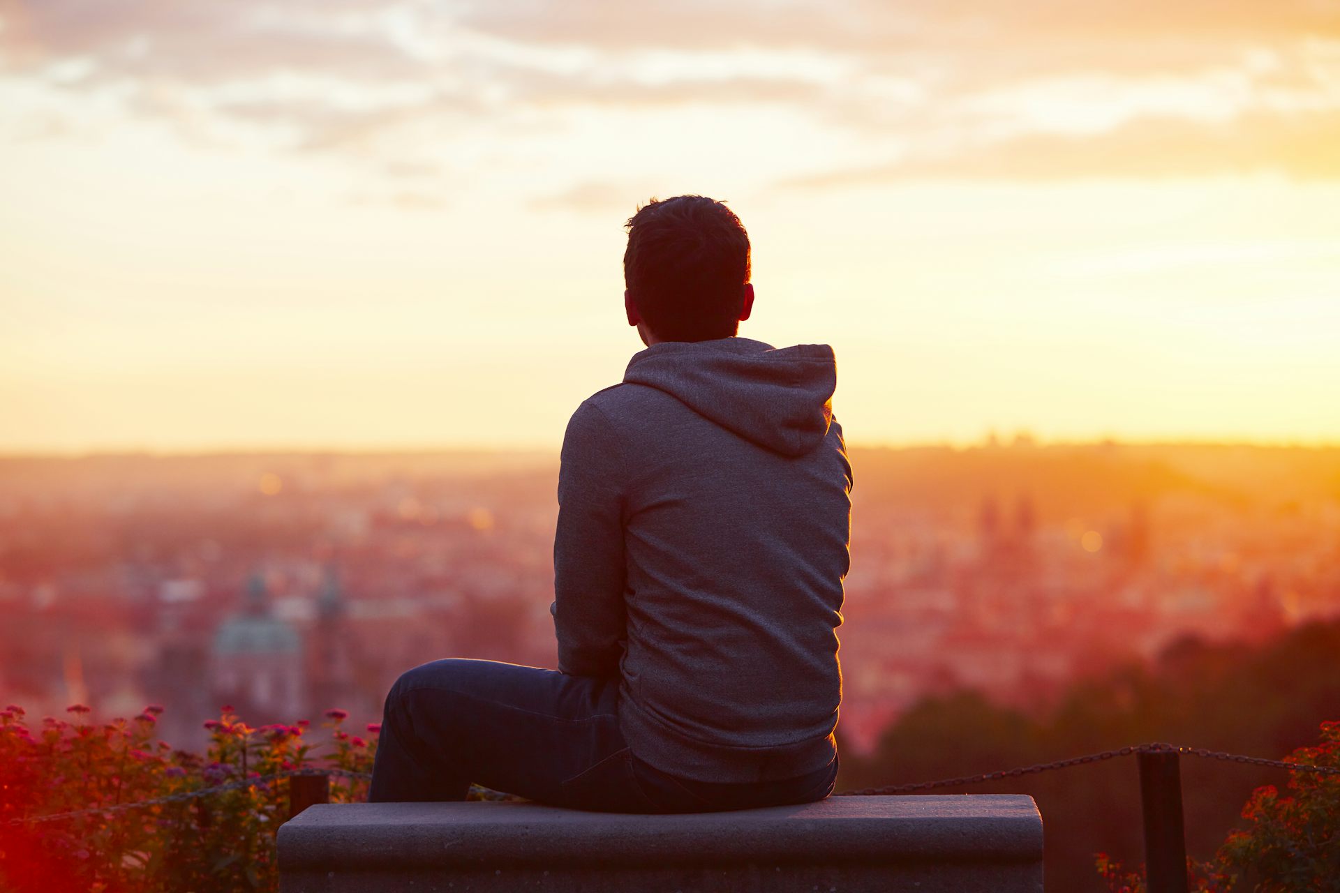 A man sits alone looking over a cityscape